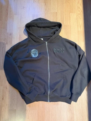 Broken planet zip up hoodie - Snygg broken planet hoodie med stort spindelnät tryck på ryggen i puffprint. Varsamt använd, bra skick. Storlek Medium, kan även passa large 100% bomull. Pris kan diskuteras.