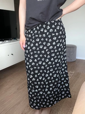 Y2K svart midikjol med fickor och vita blommor - Flowy midikjol med små vita blommor, stretch i midjan och fickor från Lager157. Mycket bra skick! Styla y2k eller basic med baby tee, cardigan eller oversized t-shirt <3