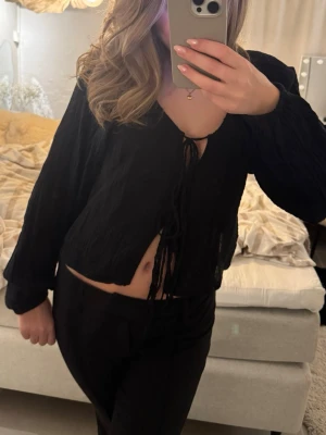 Svart croppad blus med snörning - Säljer en svart croppad blus med långa ärmar och snygg snörning framtill. Toppen har en luftig känsla och passar perfekt till både jeans och kjol. Enkel men trendig design som är lätt att styla.💓💓😙😙