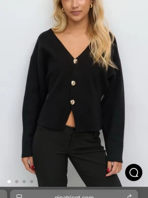 Svart kofta med guldknappar Gina Tricot - Svart kofta från Gina Tricot med djup V-ringning och fyra dekorativa guldknappar framtill.