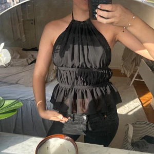 Svart halterneck topp med volang - Säljer denna otroligt fina svarta toppen. Som har en öppen rygg som man knytter!! Wow wow 🤍