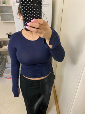 Mörkblå långärmad topp med slits i slutärm - En enkel och stilren mörkblå långärmad topp med tight passform. Perfekt att matcha med jeans eller kjol för en clean look. Tillverkad i mjukt material som sitter skönt mot kroppen.