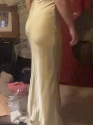 Ljusgul  långklänning i silke - Elegant långklänning i ljusgult silke med smala axelband, djup v-ringning och öppen rygg. Klänningen har en slät, glansig yta och följsam passform som ger en lyxig känsla. Nypris på denna klänningen är 3200.