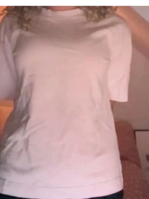 Vit basic t-shirt i bomull - Enkel vit t-shirt i mjuk bomull med rund hals och korta ärmar. Perfekt för en clean och avslappnad stil. Passformen är normal och modellen är klassisk utan tryck eller detaljer.