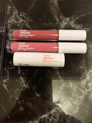 Indy Beauty rosa läppstift trio - Säljer tre snygga läppstift från Indy Beauty i olika nyanser av rosa. Två är flytande med vita lock och en är i klassisk stiftform. Alla är 100% veganska och har en modern, stilren design med märkets logga tryckt på hylsorna.
