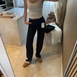 Mörkblå kostymbyxor från madlady  - Säljer ett par mörkblå kostymbyxor med rak passform och hög midja. Byxorna har klassisk design utan synliga detaljer framtill och är perfekta för en clean och stilren look. Materialet ser ut att vara mjukt och följsamt, vilket ger en snygg siluett.