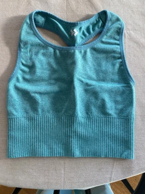 Turkos sport-bh med ribbad kant - Säljer en turkos sport-bh från lager157 med ribbad kant nedtill och brottarrygg. Tillverkad i stretchigt material som passar perfekt för träning.