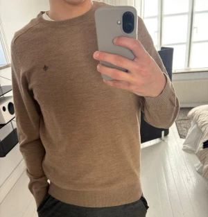 Beige merinoullströja från Morris - Beige tröja från Morris i mjuk merinoull. Klassisk rund halsringning och diskret logga broderad på bröstet.  Ca 180 cm lång och väger 80 kg, tröjan är i strlk L