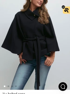 Mörkblå cape med knytband - Mörkblå poncho kappa från Gina tricot. Har hög krage med knappdetalj och en mjuk, något tjockare kvalitet. Använt endast 1 gång och säljer just därför.nypris 500 säljer för 400.