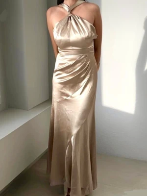 Maxiklänning halterneck Asos - Beige/champagnefärgad långklänning från Asos. I bra skick med några enstaka små repor som satin lätt får samt ett hål i en söm som har lagats (se bild 2) men inget man tänker på😇storlek S/36