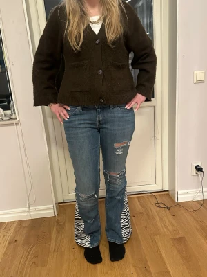 Blå jeans med zebra bootcut - Unika blå jeans med slitningar och zebramönstrade paneler nedtill på benen. Modellen är utsvängd och har en cool, trendig vibe. Perfekta för dig som vill sticka ut och gillar statement-plagg. Innerbenslängden är 78 och midjemåttet är 40. Modellen är 169 cm lång!💓kolla in vår profil för fler plagg!💙