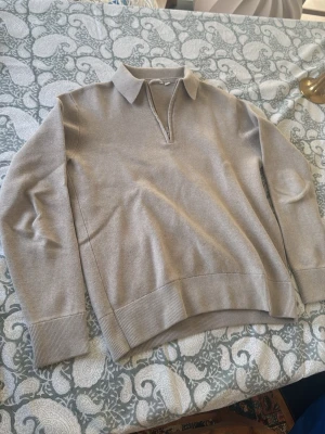 Schysst Half-zip från Dobber - Snygg beige stickad tröja med krage och v-ringning utan knappar. Tröjan har långa ärmar och breda ribbade muddar vid ärmslut och nederkant. Perfekt för en stilren och avslappnad look. Perfekt för våren. Priset kan diskuteras!