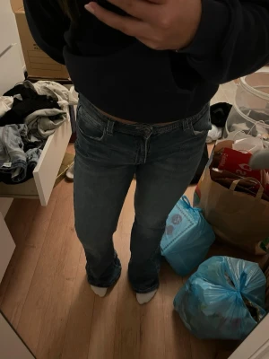 Low Waist jeans - Säljer ett par klassiska blå bootcut jeans från Gina tricot med snygga sömmar och broderad logga på bakfickan. Jeansen har låg  midja. Perfekta till sneakers eller boots! Passar som S vanlig storlek men är från Gina Young. Lite slitage längst ner.