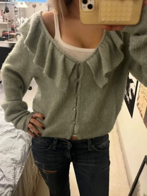 Ljusgrön kofta med volang - Jätte gullig mintgrön kofta från h&m som är slutsåld. En av knapparna är sönder som syns på bild men jag har löst det genom att knyta fast knappen på plats. Så skönt material och inga övriga defekter. Skriv vid frågor 🤗