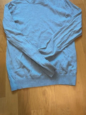 Ljusblå basic tröja - En enkel och stilren ljusblå tröja med rund hals och långa ärmar. Tröjan är tillverkad i ett tunt, mjukt material och har ribbade muddar vid ärmslut och nederkant. Perfekt att matcha med jeans eller kj sop.