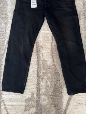 Svarta raka jeans från Zara  - Säljer ett par svarta jeans från zara med rak passform och klassisk femficksdesign. Jeansen har en enkel look utan slitningar och är tillverkade i ett mjukt denimtyg som känns bekvämt. Perfekta för dig som gillar en clean och stilren stil.
