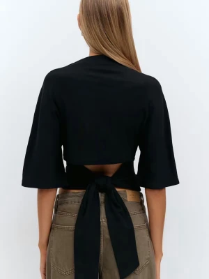 Svart croppad topp med knyt - Trendig svart croppad topp med halvlånga ärmar och snygg knytning i ryggen som ger en öppen rygg-effekt. Perfekt för att lyfta din outfit med en snygg detalj. Toppens material är mjukt och stretchigt.