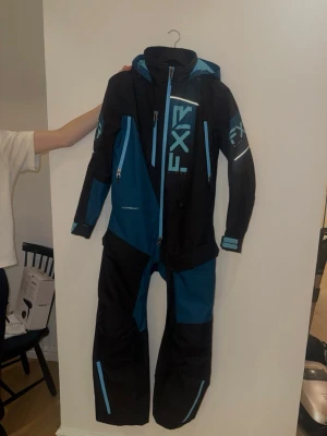 Svart och blå skoteroverall från FXR - Säljer en skoteroverall från FXR i svart och blått. Den är helt oanvänd och fordrad, nyskick! 