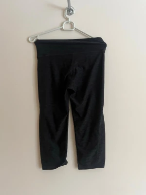 Svarta capri leggings med hög midja - Säljer ett par svarta capri leggings med hög midja. De är stretchiga och har en enkel, stilren design utan synliga loggor eller detaljer. Perfekta för träning eller chill dagar. Materialet känns mjukt och följsamt.