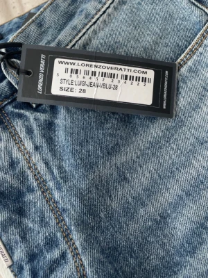 Ljusblå slitna jeans Lorenzo Veratti - Säljer ett par ljusblå jeans från Lorenzo Veratti med slitna detaljer och klassisk femficksmodell. Jeansen har en avslappnad passform och är tillverkade i denim med snygga slitningar framtill. Perfekta för en trendig och avslappnad look.