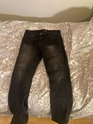 Svarta raka jeans med tvättad look - Säljer ett par svarta jeans med rak passform och tvättad, lite sliten look. Klassisk femficksmodell med knapp och dragkedja fram. Jeansen är tillverkade i denim och har en avslappnad vibe som passar perfekt till streetwear. Pris kan diskuteras. Bara Skriva om frågor