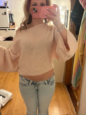 Ljusrosa stickad tröja med vida ärmar - Supermjuk och fluffig ljusrosa stickad tröja med croppad passform och vida ärmar. Tröjan har en avslappnad look och är perfekt för en trendig och bekväm stil. Materialet känns lätt och mysigt.