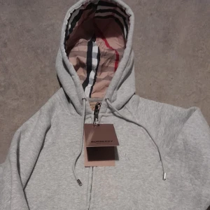 Grå hoodie från Burberry med huva - Hej jag säljer den här burberry koftan för jag köpte fel storlek 🚨Pris kan diskuteras