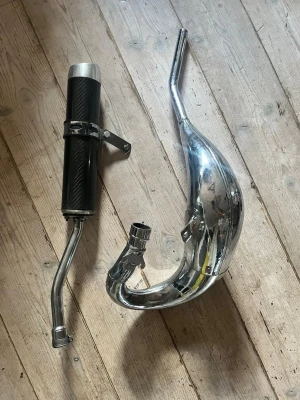 Avgassystem till moped - Säljer ett avgassystem till moped med ett kromat expansionsrör och en svart ljuddämpare med kolfiberlook. Passar dig som vill uppgradera ljud och prestanda på din moppe. Monteringsfäste ingår.