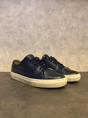 Axel Arigato Clean 90 - Säljer dessa Axel Arigato Clean 90 i bra skick! Skorna har matchande mörkblå snören och stilren design som passar till det mesta. Perfekta för dig som gillar en clean och tidlös look.