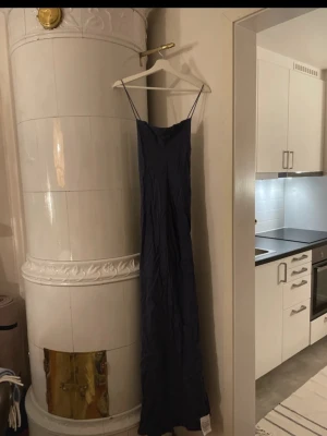 Mörkblå klänning - Elegant mörkblå långklänning med smala axelband och öppen rygg. Klänningen har en slimmad passform upptill och faller snyggt längs kroppen. Perfekt för festliga tillfällen och bal. Helt oanvänd och fortfarande i orginal förpackning🌟 köpt för 1700kr säljer för 550kr!!
