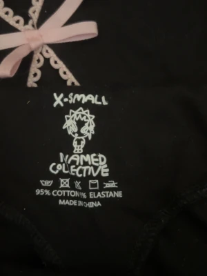 Named Collective leggings med rosetter - Säljer ett par svarta leggings från Named Collective i storlek XS. De har unika detaljer med rosa rosetter och spets längs benen. Materialet är 95% bomull och 5% elastan vilket gör dem stretchiga och bekväma. Perfekta för dig som vill sticka ut med coola detaljer! Jag säljer då de är för små för mig. Aldrig använda förutom när jag provade de och tog bild med dem. 