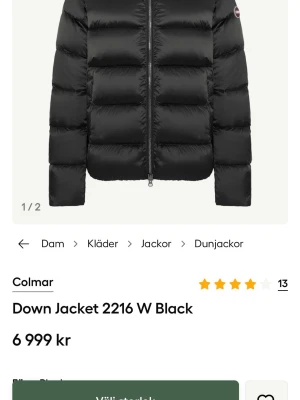 Colmar jacka dam - Snygg svart dunjacka från Colmar med glansig finish och stor vadderad huva. Jackan har breda kanaler, två sidofickor med dragkedja och en Colmar-logga på ärmen. Perfekt för kalla vinterdagar och riktigt varm tack vare dunfyllningen.