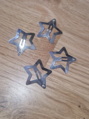 Hårspännen - Fyra stycken hårspännen i metall med stjärnformad design och blank silvrig finish. Perfekta för att ge frisyren en lekfull och trendig touch. Lätta att använda och passar till många olika looks. Helt nya