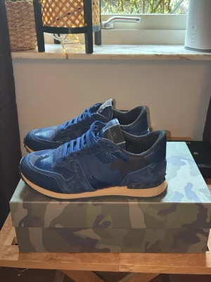 Valentino Garavani Rockrunner Camo Navy Blue EU40 – Helt nya - Valentino Garavani Rockrunner sneakers i navy blue/camo colorway.  Storlek EU40. Helt nya / oanvända.  Kommer komplett med:   Originalbox  Dustbag  Extra snören  Väldigt clean och ovanlig colorway. Perfekt skick.  Skickas spårbart. Fler bilder finns vid intresse. Bud accepteras!