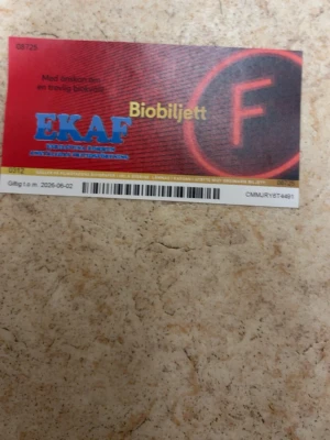 Biobiljett från EKAF - En biobiljett från EKAF med röd och svart design samt tydlig F-symbol. Giltig till 2025-06-02 och kan användas för ordinarie filmvisningar på Filmstaden. Baksidan har instruktioner och säkerhetskod. Perfekt för filmälskare.
