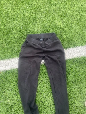 Svarta mjukisbyxor från PeakPerformance - Svarta mjukisbyxor från  PeakPerformance med ribbad midja och dragsko. Byxorna har två sidofickor och är gjorda i mjukt, fleeceliknande material på insidan. Perfekta för en avslappnad stil och chill dagar.