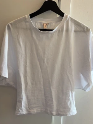 Vit t-shirt - En klassisk vit t-shirt med rund hals och korta ärmar. Tillverkad i mjuk bomull och passar perfekt till jeans eller shorts. Enkel och stilren design som funkar till det mesta.