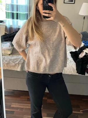 Beige stickad tröja med kort ärm - Säljer en beige stickad tröja med boxig passform och korta ärmar. 