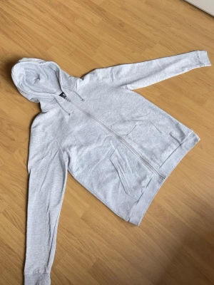 SOC grå zip hoodie strl S - Grå zip hoodie från SOC i mjukt och skönt material. Enkel och clean design som passar till allt. Storlek S med slim/normal passform. Bra skick och perfekt som vardagshoodie.  Modellen på bilden är ca 185 cm lång och väger ca 78 kg för referens.