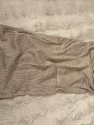 Beige ribbad långkjol - Snygg beige långkjol i ribbat material med slits bak. Kjolen har en rak passform och är perfekt för dig som gillar en stilren och enkel look. Passar till många olika outfits och är superenkel att matcha.