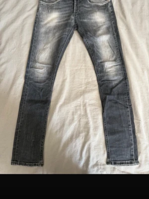 DonDup George jeans - Snygga grå slim fit jeans med slitna detaljer och ljusa partier på låren och knäna. Klassisk femficksmodell med dragkedjegylf och raka ben. Perfekta för en avslappnad och trendig look.