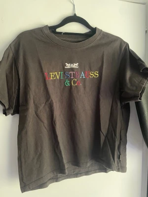Svart Levi's t-shirt med färgglatt tryck - Säljer en svart t-shirt från Levi's med färgglatt broderat 'Levi Strauss & Co.' på bröstet. Klassisk passform med rund hals och korta ärmar. I storlek XS