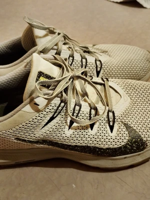 Nike vita mesh sneakers med svart swoosh - Nike sneakers i vitt meshmaterial med svart swoosh-logga och detaljer. Skorna har snörning, låg profil och gummisula med grepp. Perfekta för dig som gillar sportig stil och vill ha lätta skor med bra ventilation. Nypris runt 1700:- . Skorna är i nyskick endast använda ett fåtal gånger.