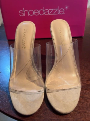 Klara pumps med transparent klack - Säljer ett par trendiga pumps från Shoedazzle med transparenta remmar och klack. Skorna har beige innersula och öppen tå. Klacken är bred och genomskinlig vilket ger en modern look. Perfekta för dig som vill sticka ut med en cool och stilren stil.