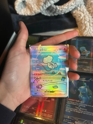 Pokémonkort Mew EX holo japansk - Säljer ett japanskt Pokémonkort med Mew EX-motiv. Kortet är holografiskt med regnbågsskimrande yta och färgglada detaljer. Perfekt för samlare eller Pokémonfans som vill utöka sin samling med en unik och snygg holo-rare.
