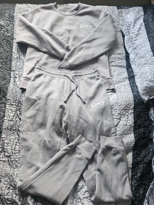 Grått loungewear-set från Primark - Mysigt loungewear-set i ljus siren/grått från Primark. Setet består av en sweatshirt med rund hals och matchande mjukisbyxor med dragsko i midjan. Båda plaggen har en avslappnad passform och är tillverkade i ett mjukt, fleeceliknande material. Perfekt för chill dagar hemma.
