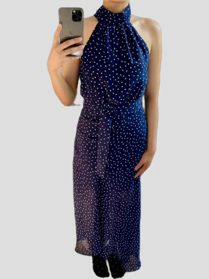 Klänning - Elegant klänning från Mango i marinblått med vita prickar. Modellen är en halterneck med knytning i midjan och har ett fint fall. Perfekt för sommarens fester eller bröllop.