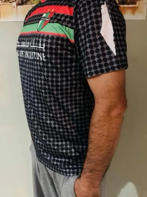 Palestina t-shirt med tryck / L - Snygg svart t-shirt från Palestino med korta ärmar och unikt mönster i form av små cirklar. Framsidan har färgade ränder i rött och grönt samt klubbens emblem. Baksidan har två vita tryck och text. Perfekt för dig som vill sticka ut.
