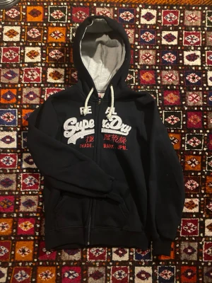 Vintage Superdry hoodie från 2000 - Säljer en otroligt fin och gammal superdry hoodie som är väldigt gammal. Den är ifrån superdrys vintage collection och är i otroligt fint skick! Hör av dig vid frågor angående hoodien!
