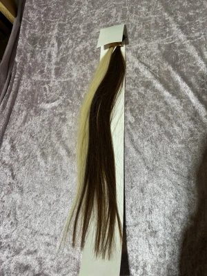 Äkta Långt löshår i brunt och blont - Säljer ett långt löshår i tvåfärgat brunt och platinablont. Löshåret har clips och keratinfästen, perfekt för att skapa kontrasterande slingor eller en unik look. Passar dig som vill ha extra längd och volym. Materialet är syntet eller äkta hår.